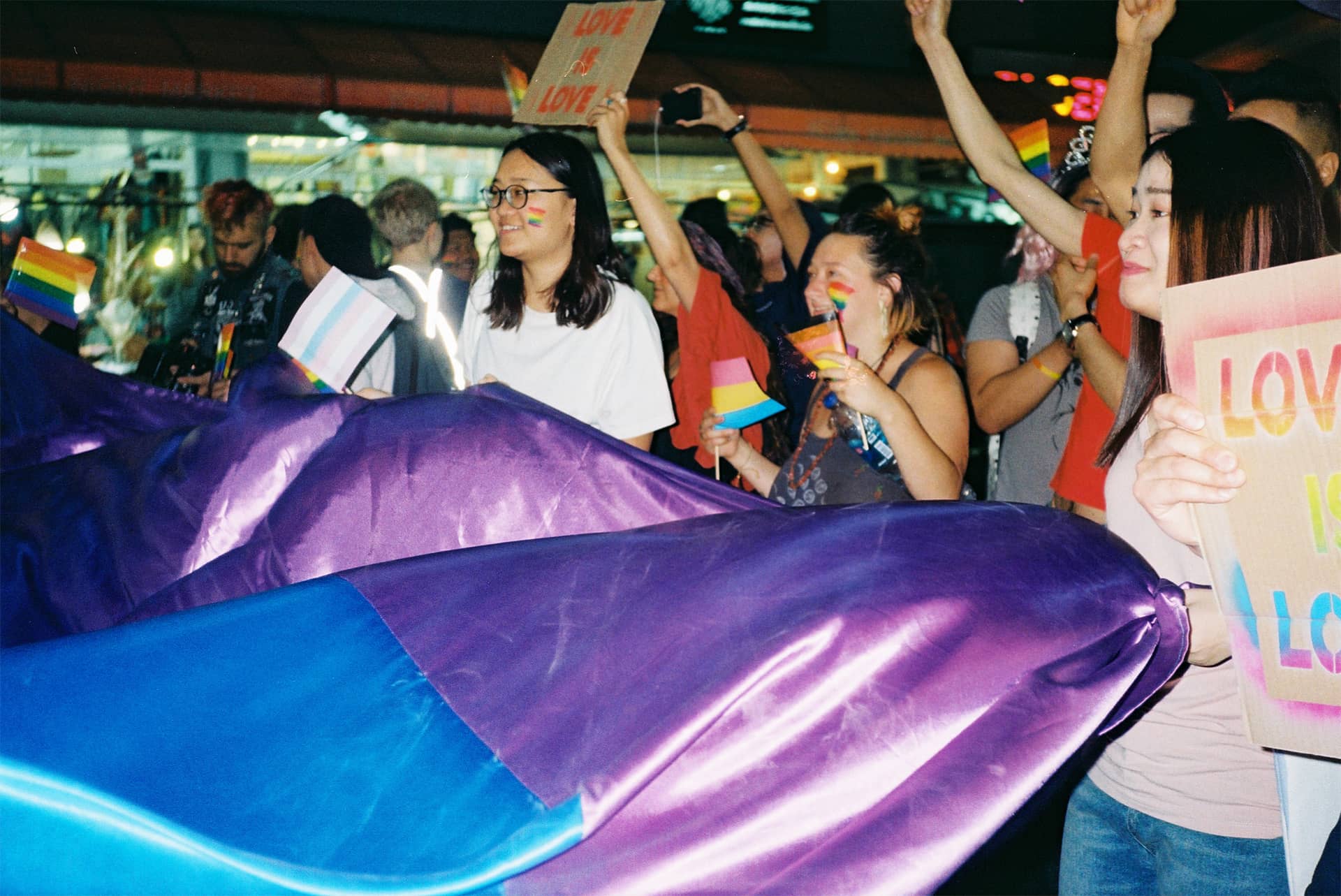 Lovewins Poster, people in a pride parade holding posters and a rainbow flag
